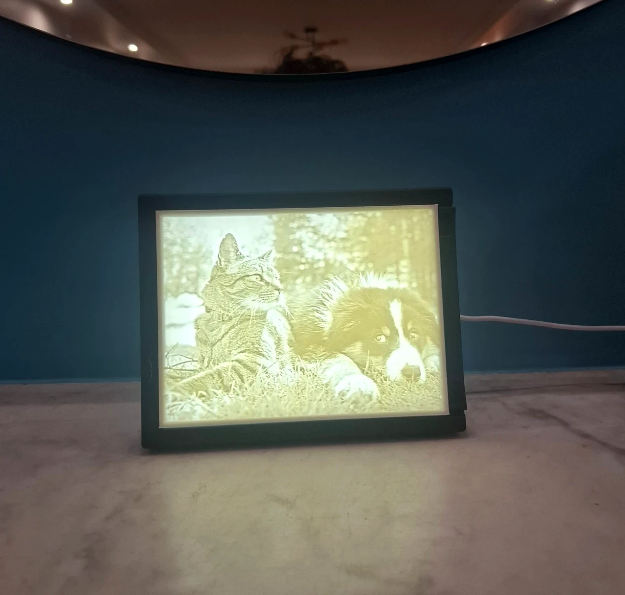Un lithophane allumé dans son cadre, posé sur une console, dans une pièce sombre